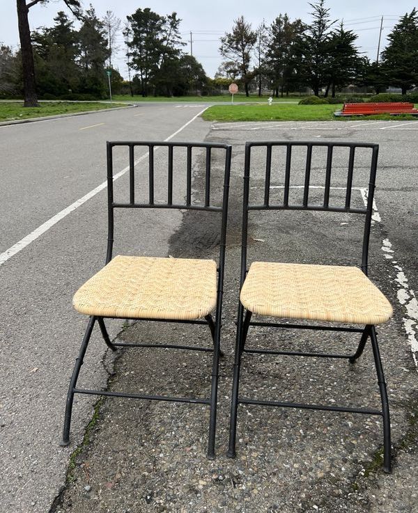 Two chairs with wicker seats are in a parking lot
