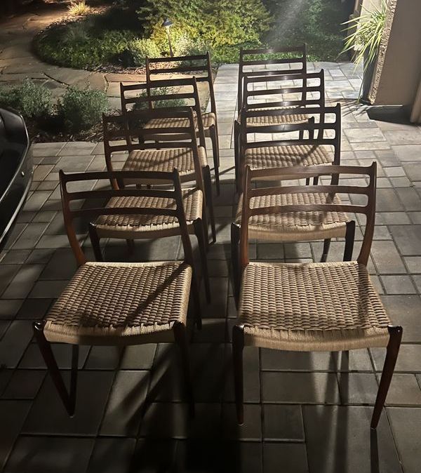 A row of chairs with wicker seats are lined up on a patio
