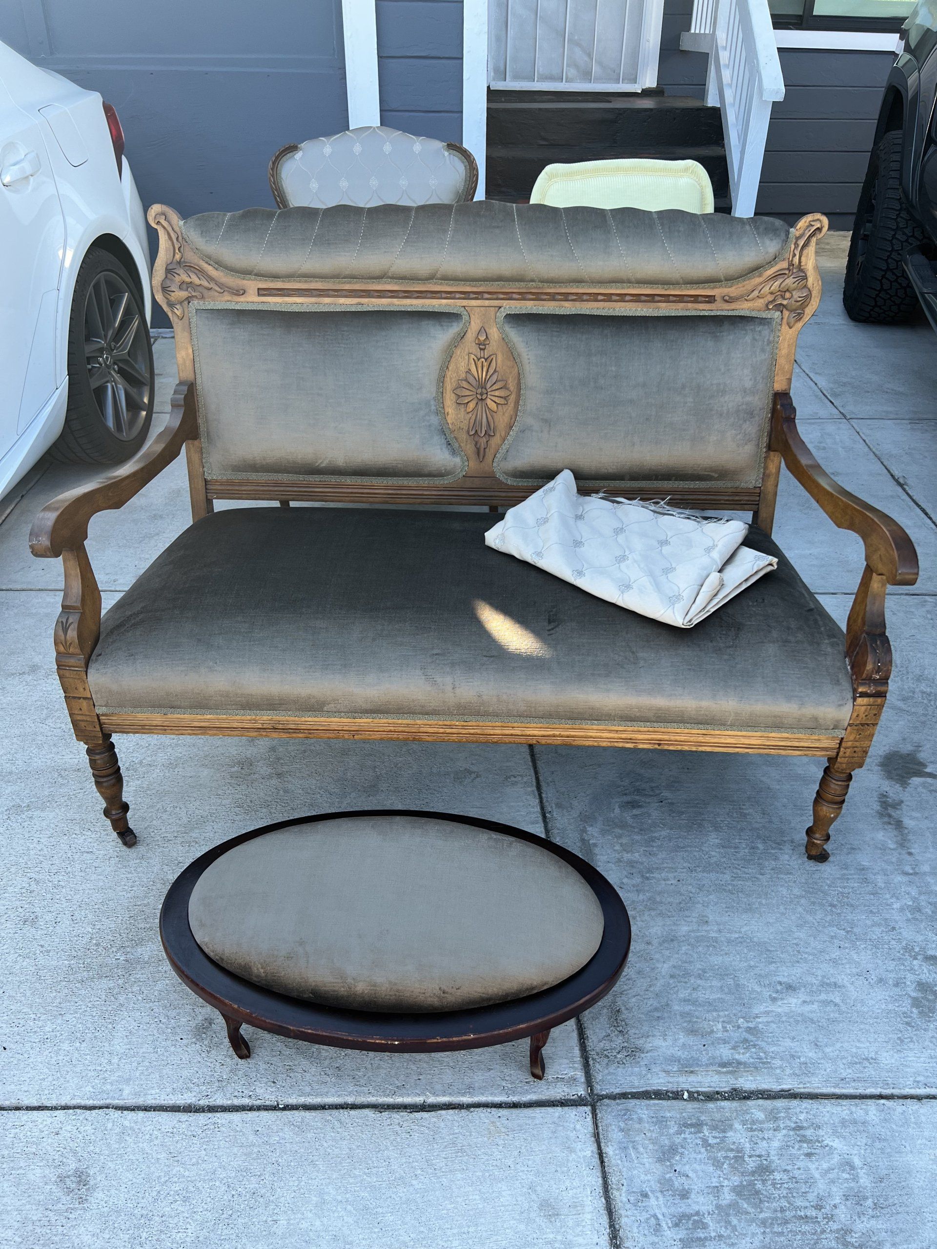 A couch is sitting on the sidewalk next to a stool