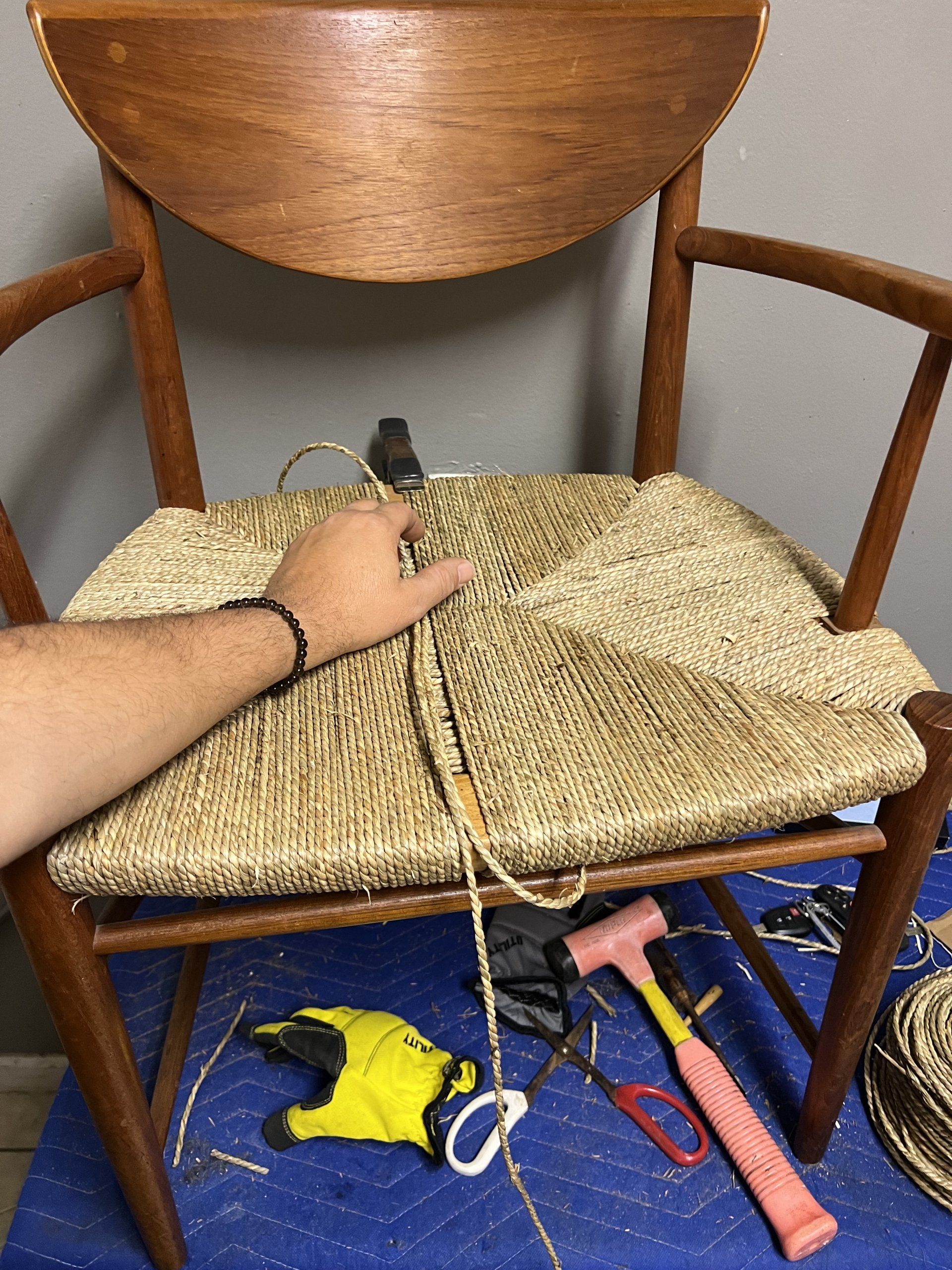 A person is working on a chair with a hammer and scissors.
