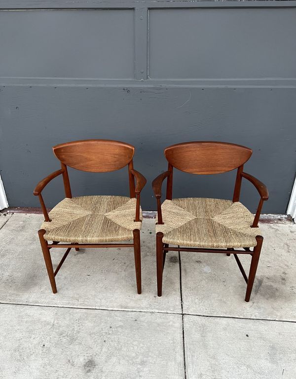 Two chairs with wicker seats are sitting on a sidewalk in front of a garage door.
