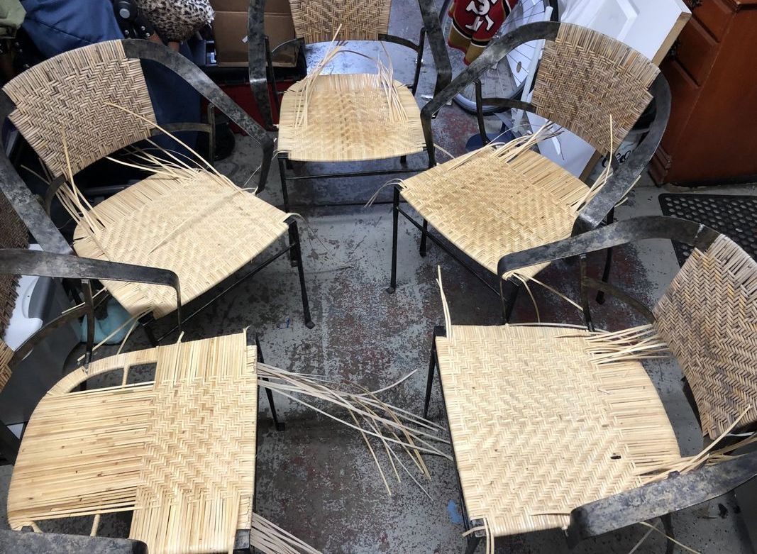 A group of wicker chairs are sitting in a circle on the ground.