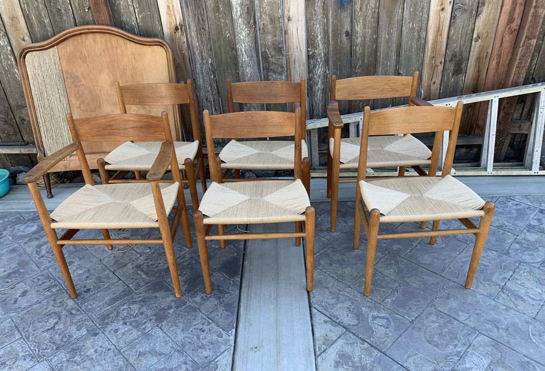 A group of wooden chairs with wicker seats are sitting on a concrete floor.