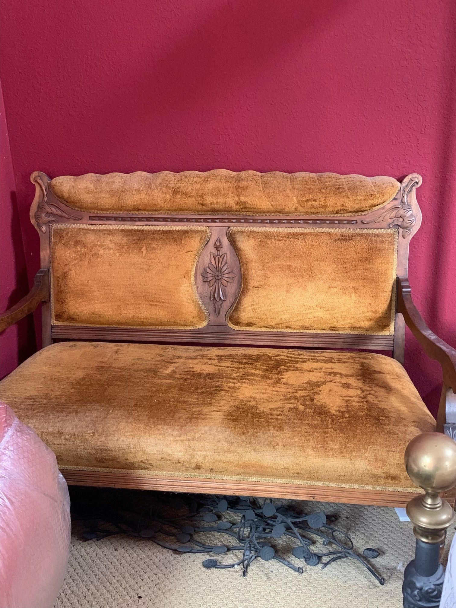 A brown couch is sitting in a room with a red wall.