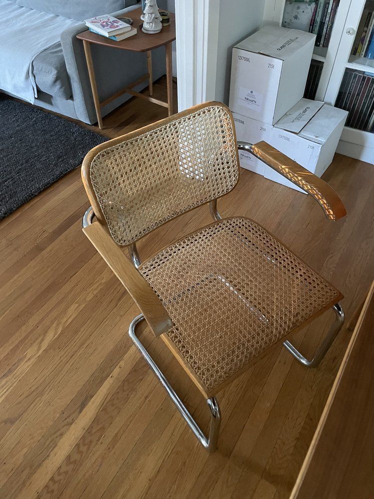 A wicker chair is sitting on a wooden floor in a living room.