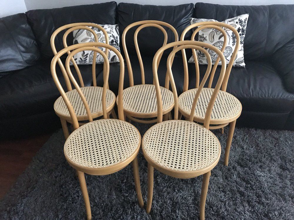 Six chairs are sitting in front of a black leather couch