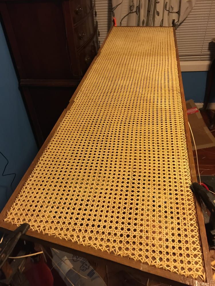 A long piece of wicker is sitting on top of a wooden table.