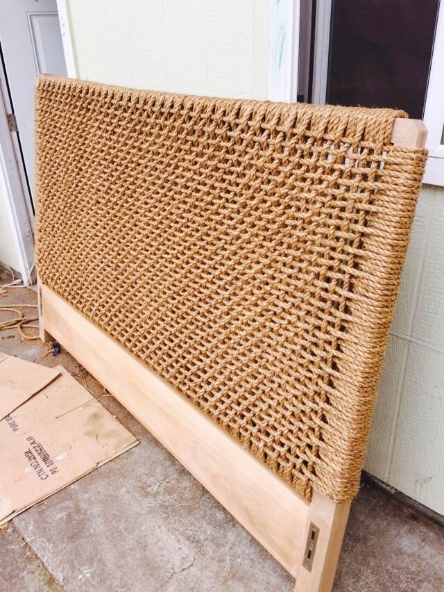 A wicker headboard is sitting on a concrete floor next to a window.
