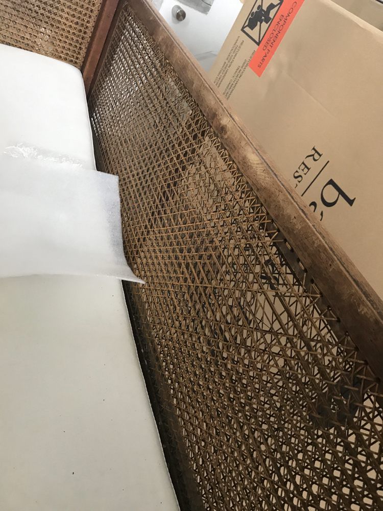 A cardboard box is sitting on top of a wicker chair.