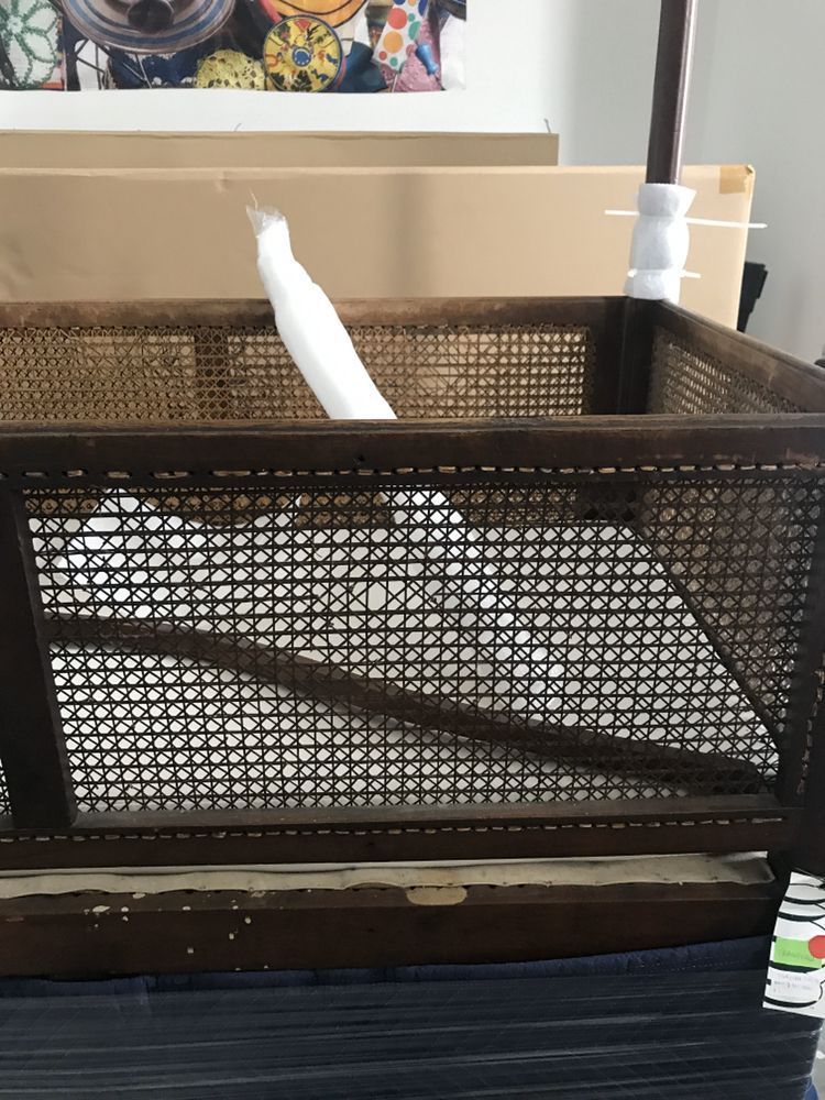 A white bird is sitting in a wire cage.