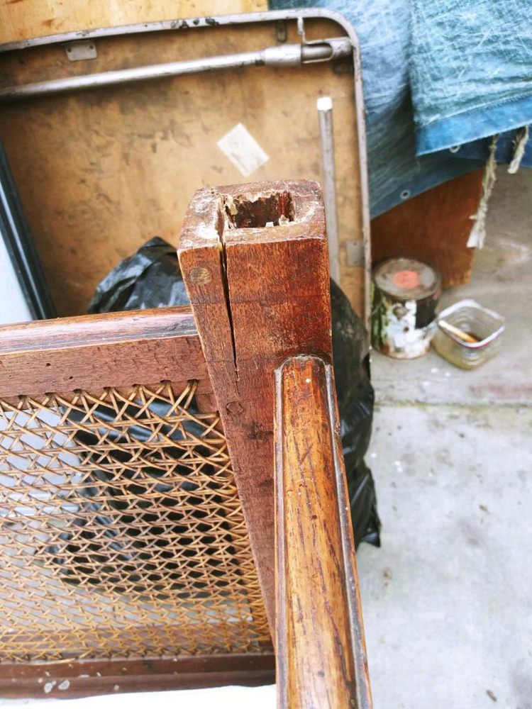 A wooden chair with a wicker back is sitting in a garage.