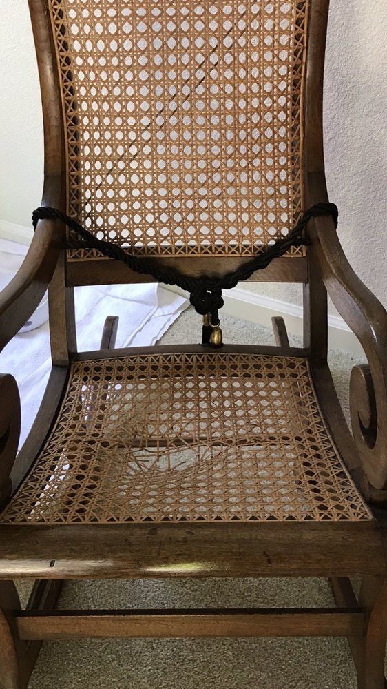 A wooden rocking chair with a wicker seat and back is sitting on the floor.