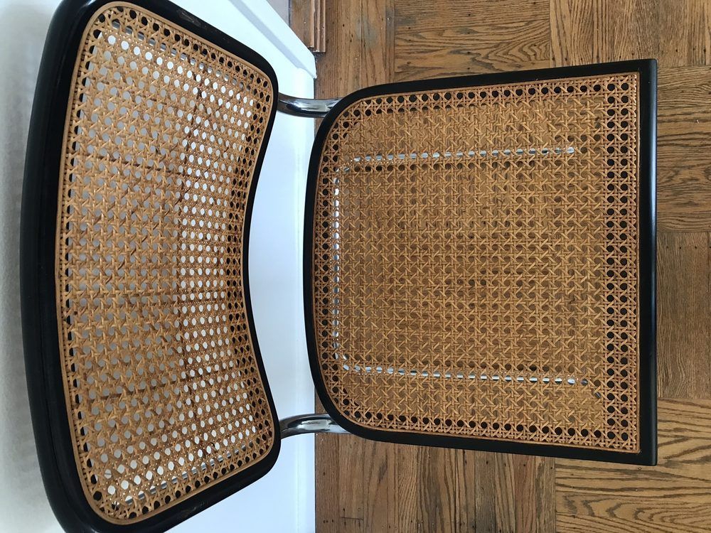 A wicker chair with a black frame is sitting on a wooden floor.