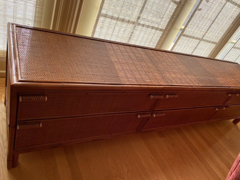 A wooden dresser is sitting on a wooden floor in front of a window.