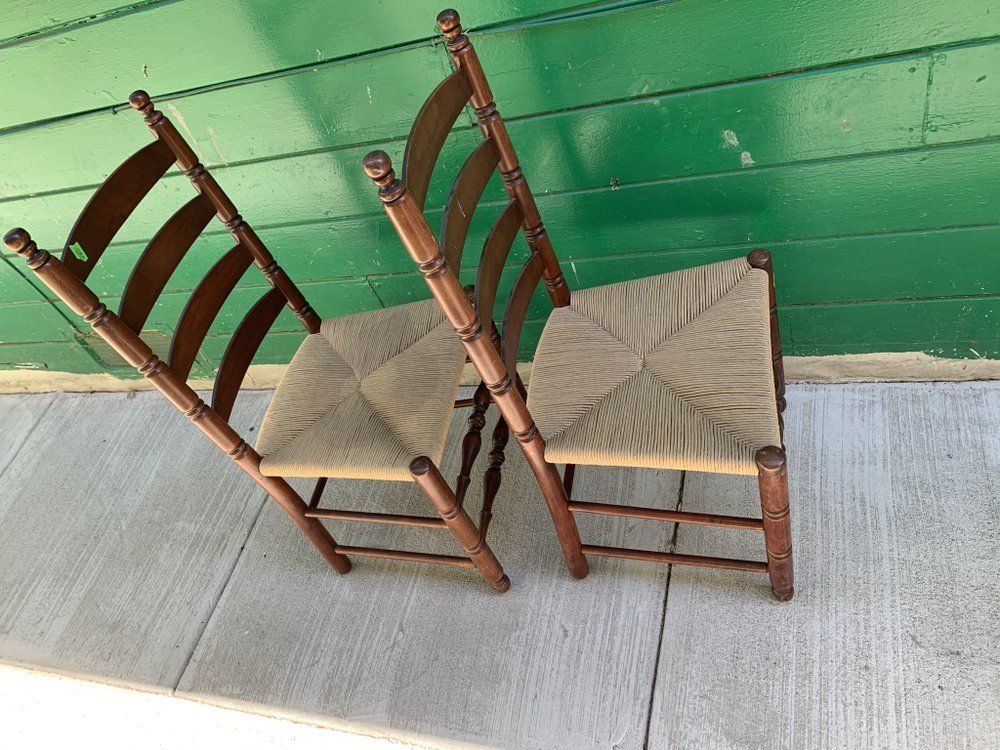 Two chairs are sitting on a sidewalk in front of a green wall