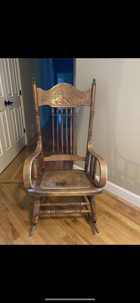 A wooden rocking chair is sitting on a wooden floor in a hallway.
