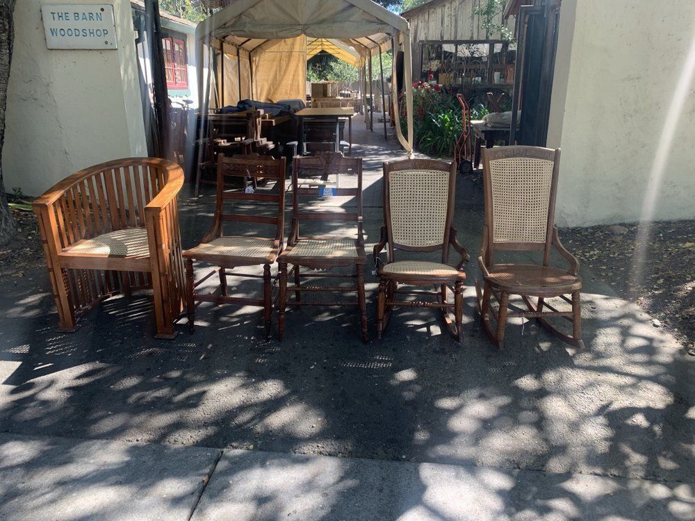 A group of rocking chairs are sitting on the sidewalk in front of a building.