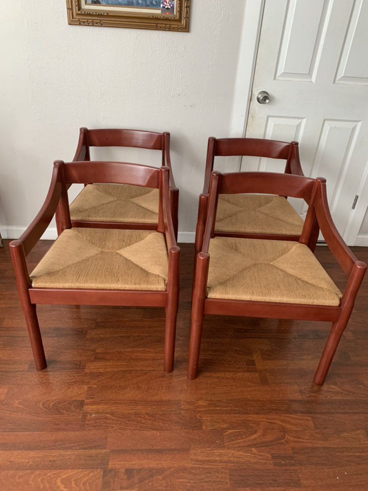 Four wooden chairs with wicker seats are sitting on a wooden floor.