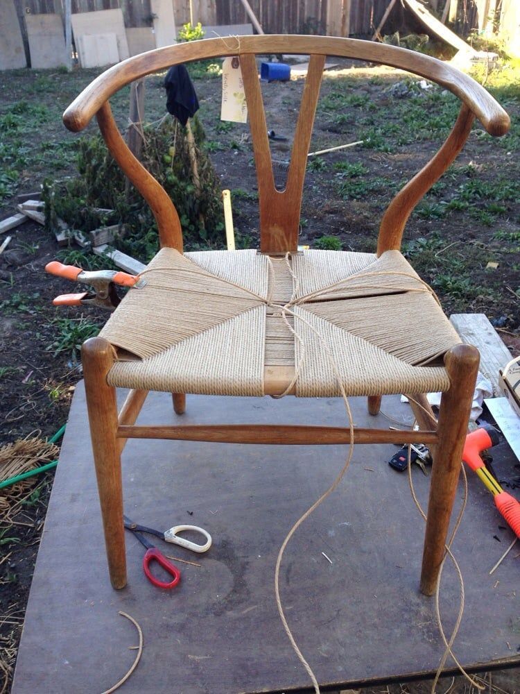 A wooden chair with a wicker seat is sitting on a wooden table.