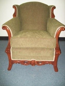 A green chair with a wooden frame is sitting on a blue carpet