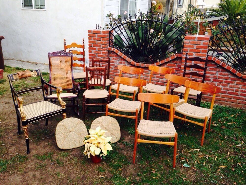 A group of chairs are sitting in the grass in front of a brick wall.
