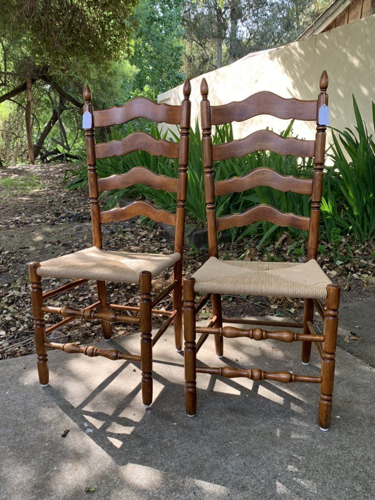 Two wooden chairs are sitting next to each other on a sidewalk.