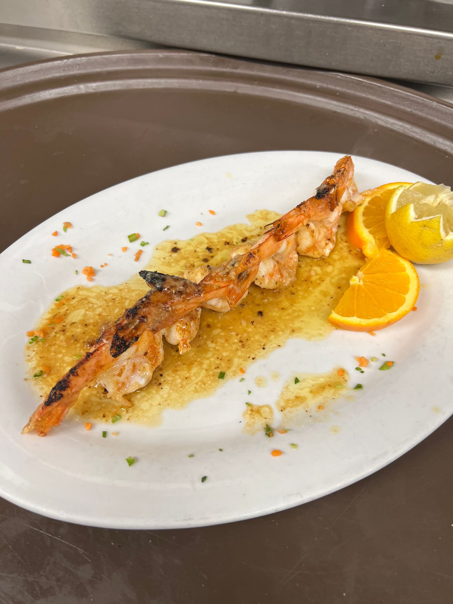 A white plate topped with shrimp and orange slices