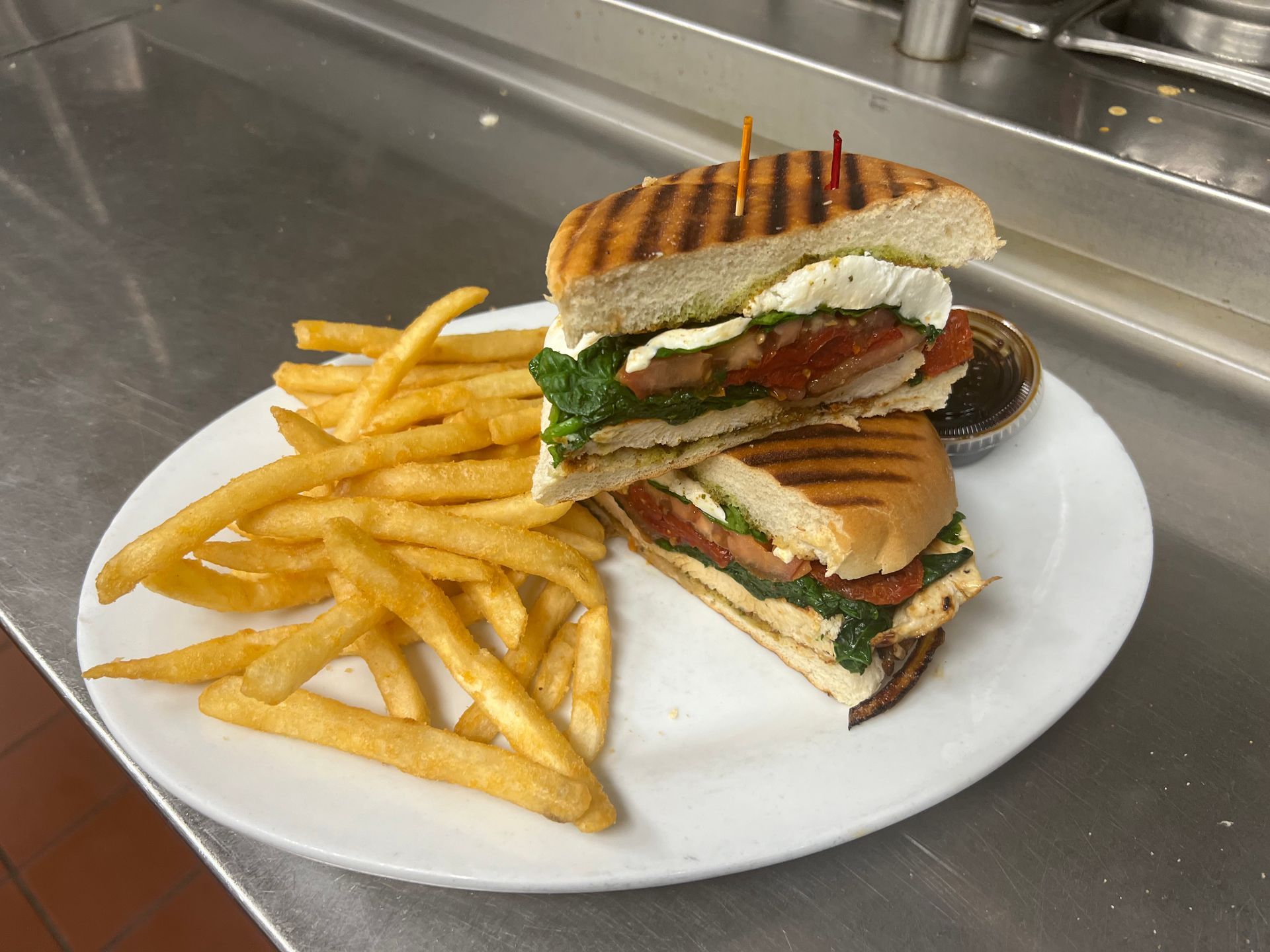 A sandwich and french fries on a white plate on a counter.