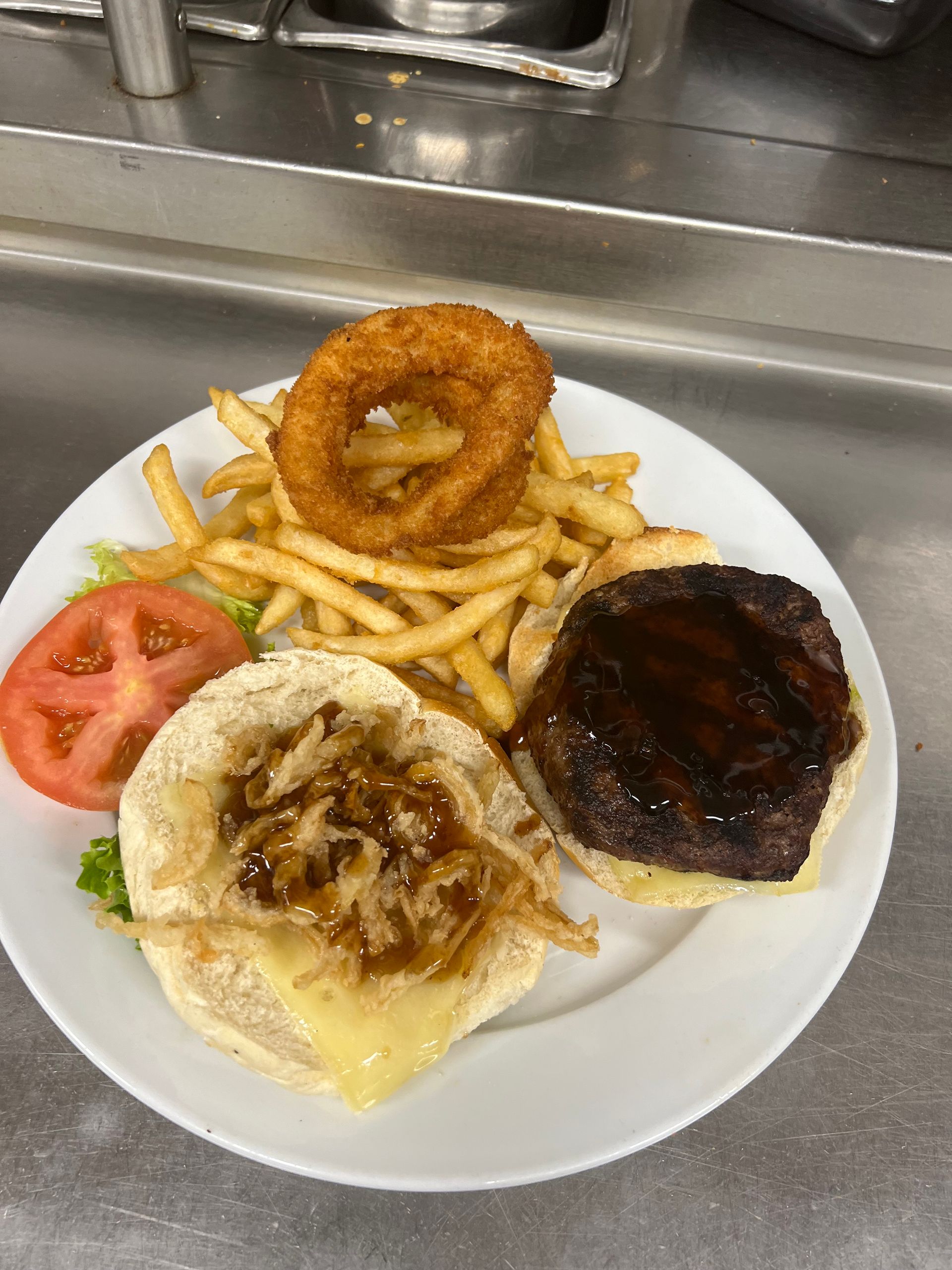 A white plate topped with a hamburger , french fries , and onion rings.