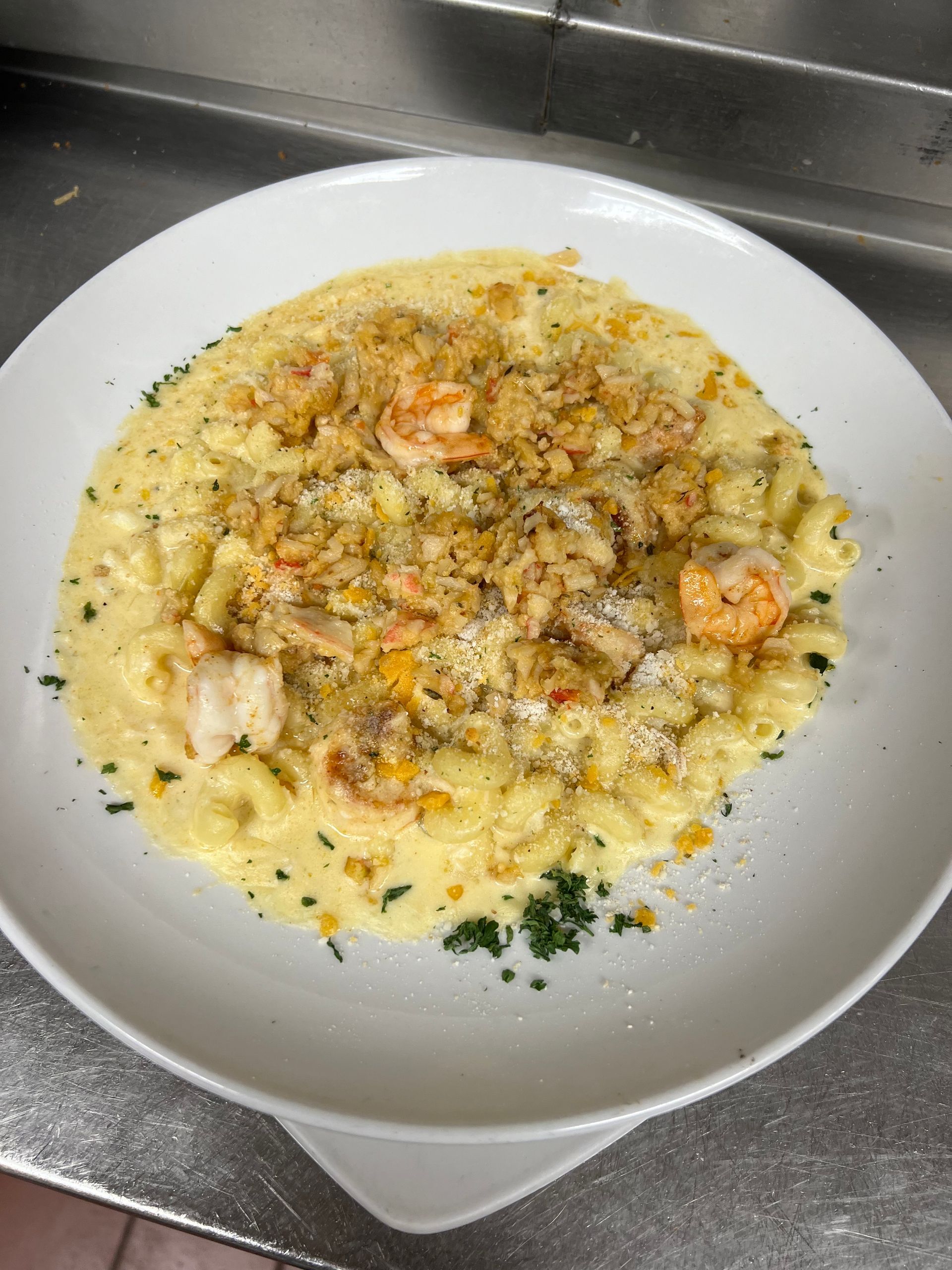 A white bowl filled with macaroni and cheese and shrimp on a table.