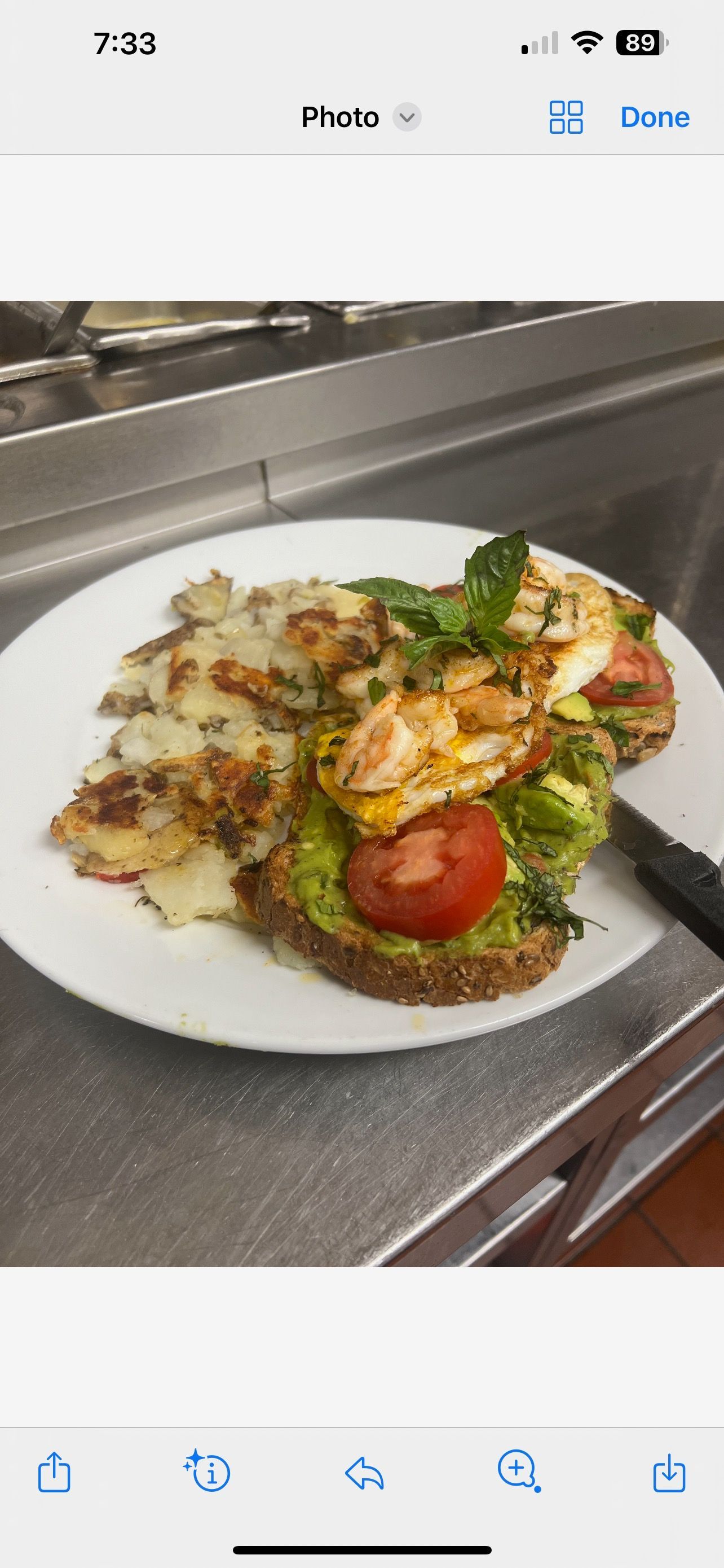 A plate of food with avocado toast , tomatoes , and potatoes on a counter.