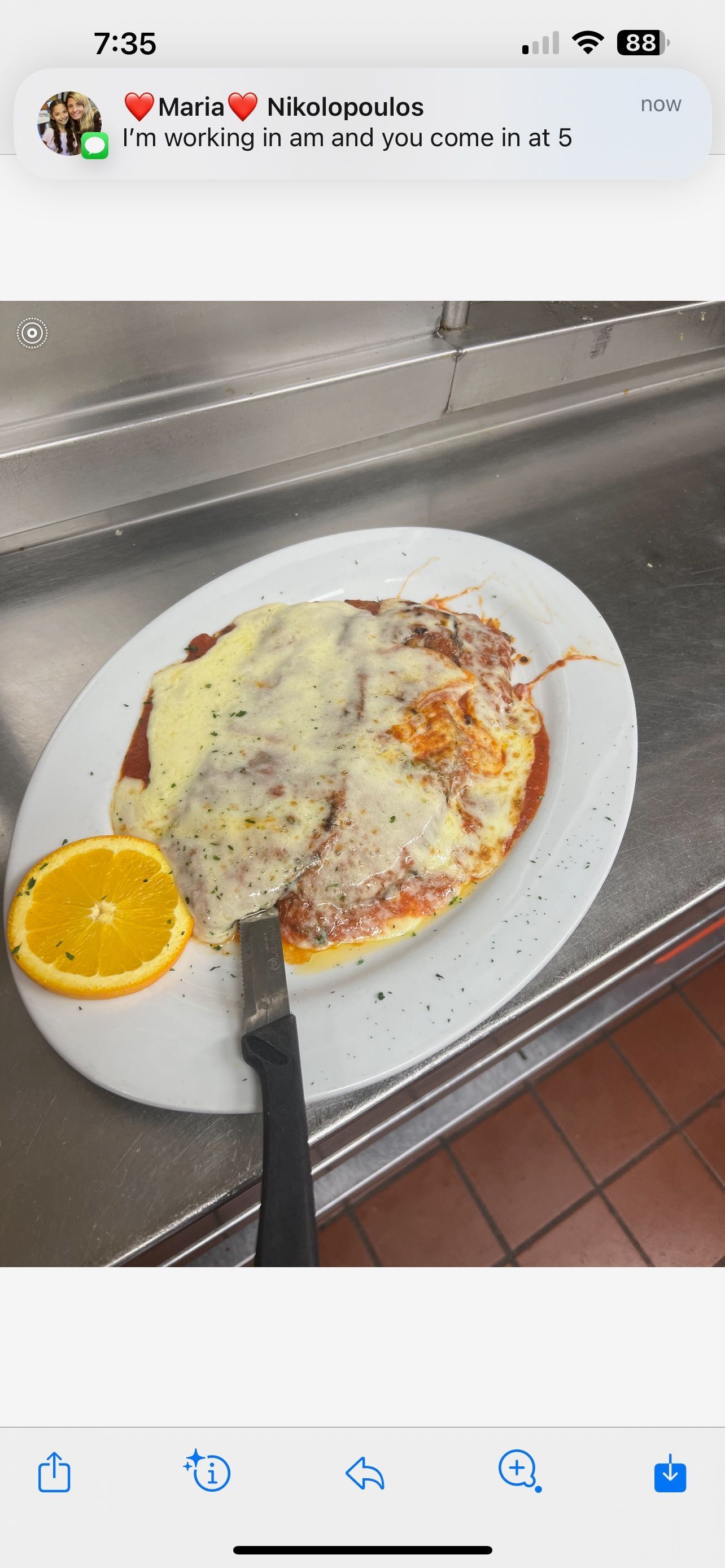 A white plate topped with a pizza and an orange slice.