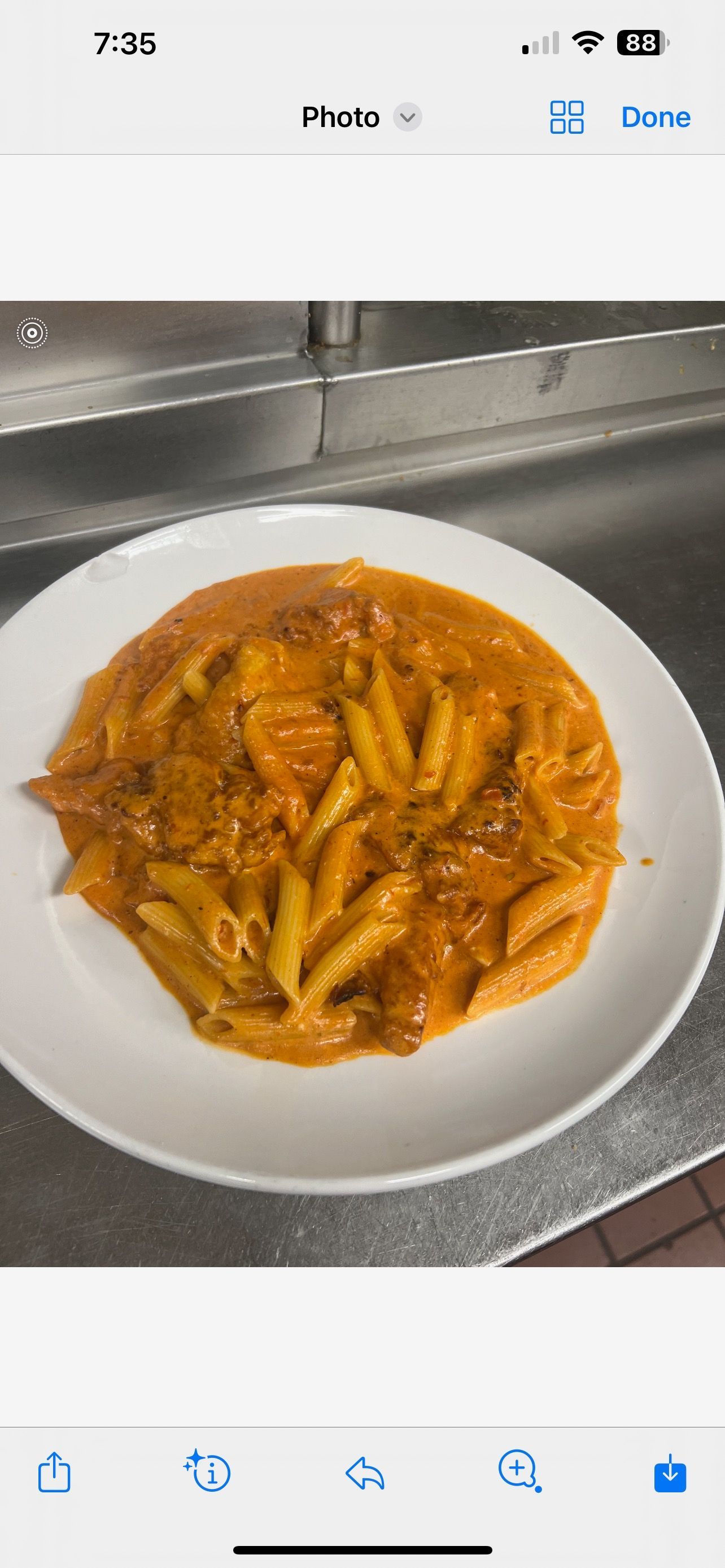 A white plate topped with pasta and sauce on a counter.