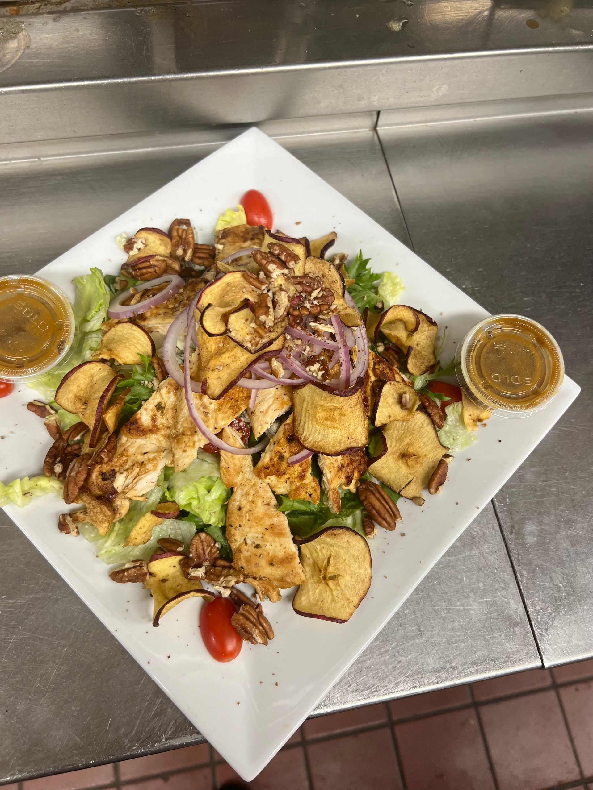 A white plate topped with a salad with chicken and banana chips