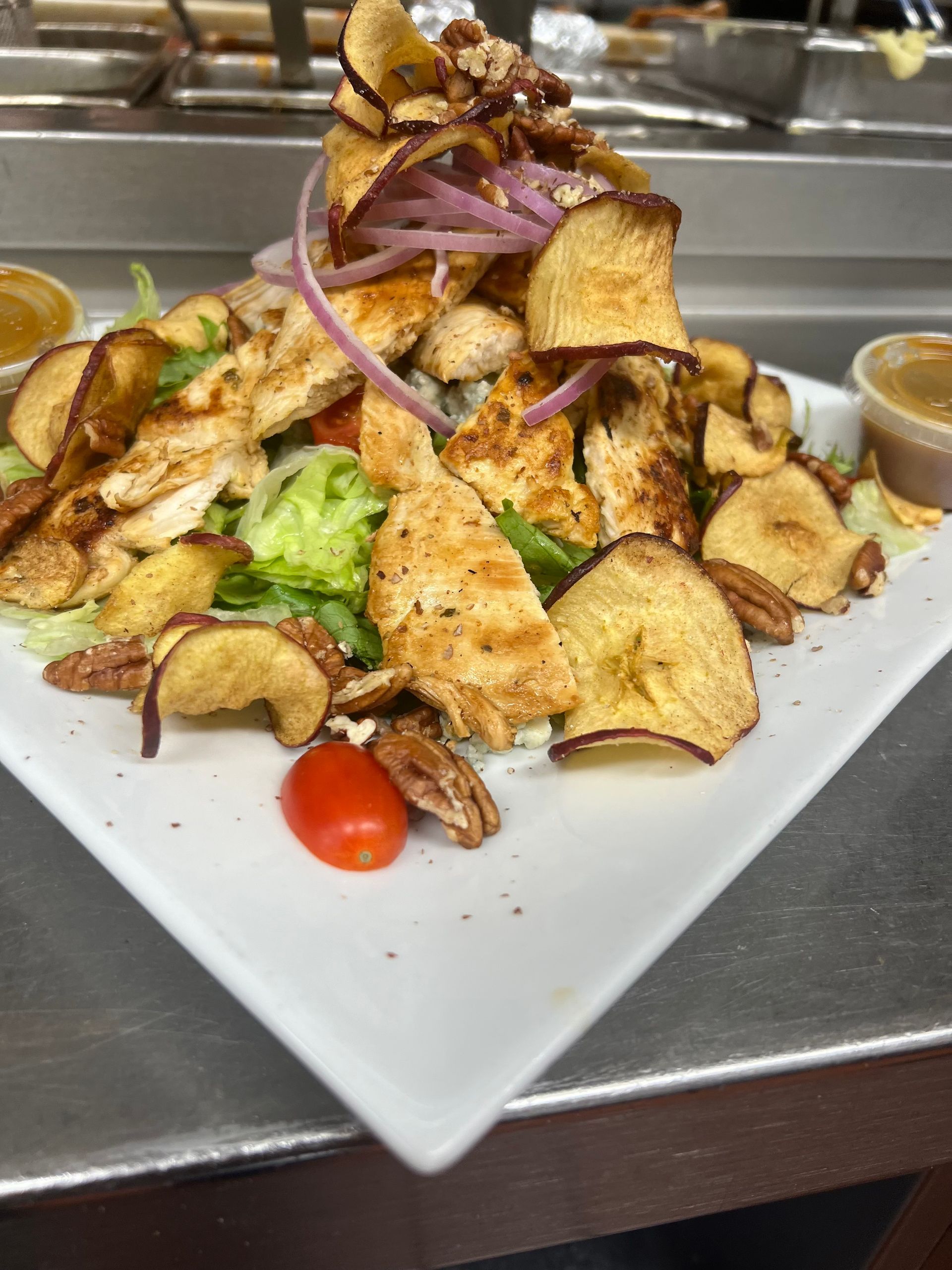 A white plate topped with a salad and chips on a counter.