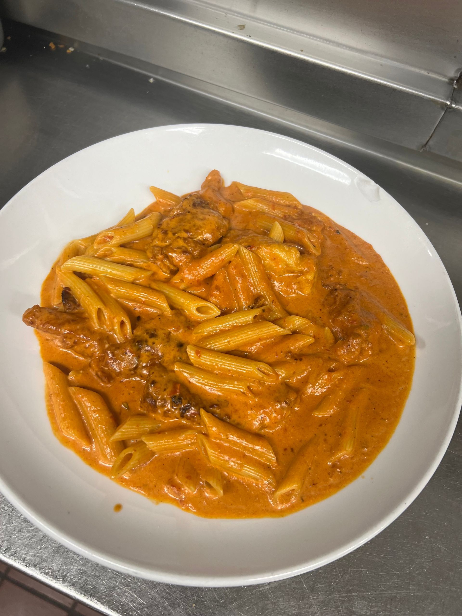 A white plate topped with pasta and sauce on a counter