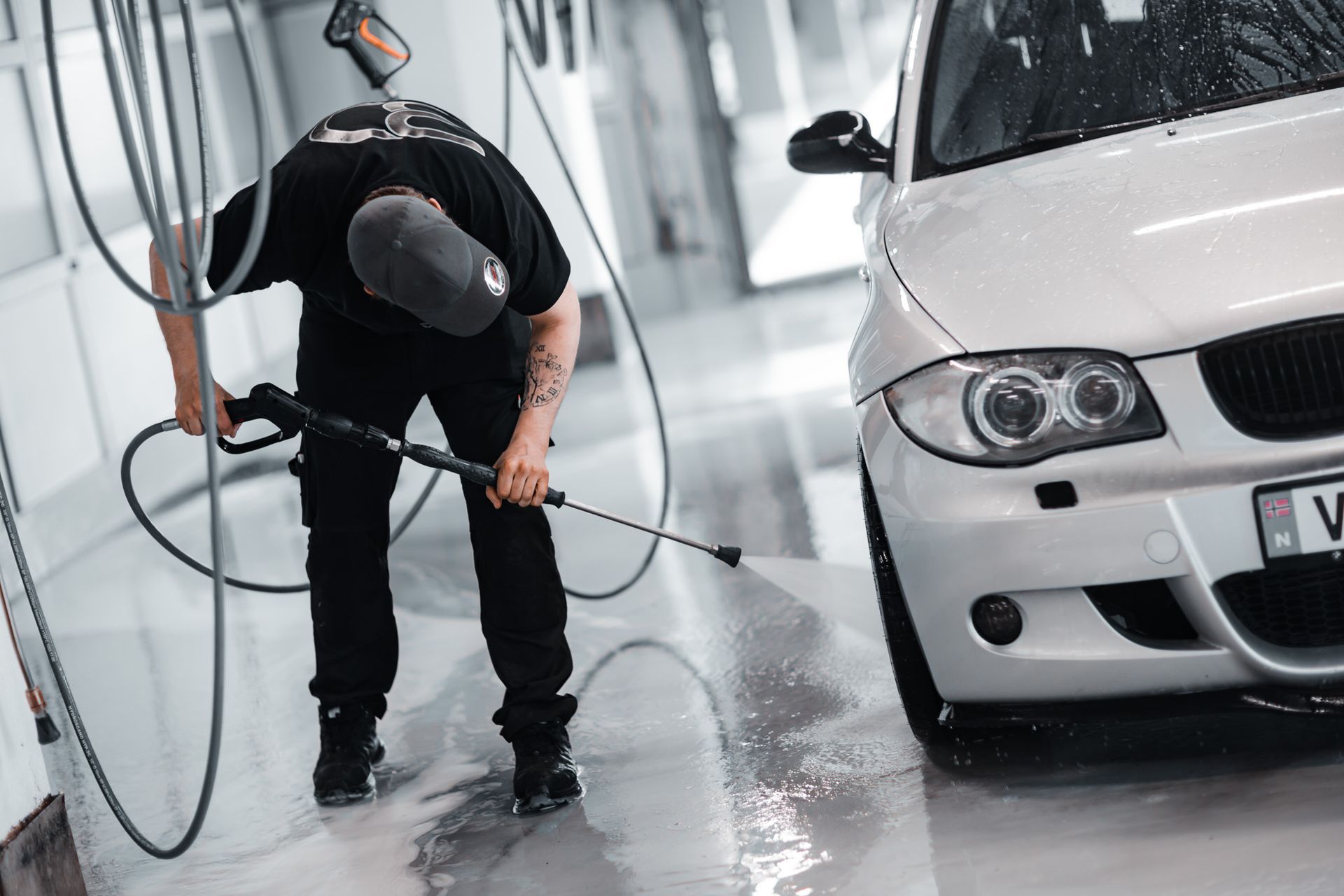 To menn vasker frontruten på en svart bil.