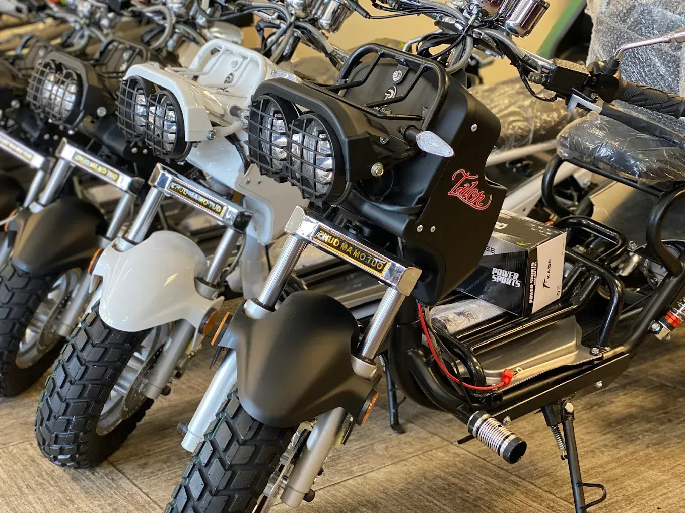 Row of electric motorcycles, black and white, in a showroom setting.