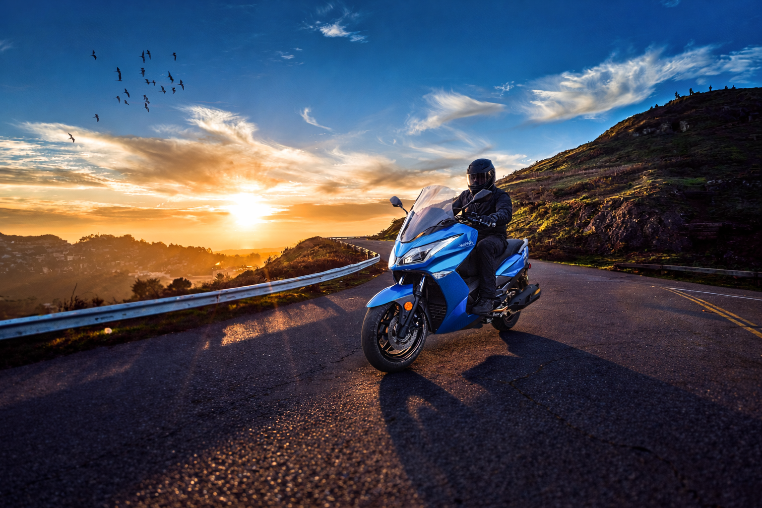 Motorcyclist on blue motorcycle at sunset on mountain road, birds in sky.
