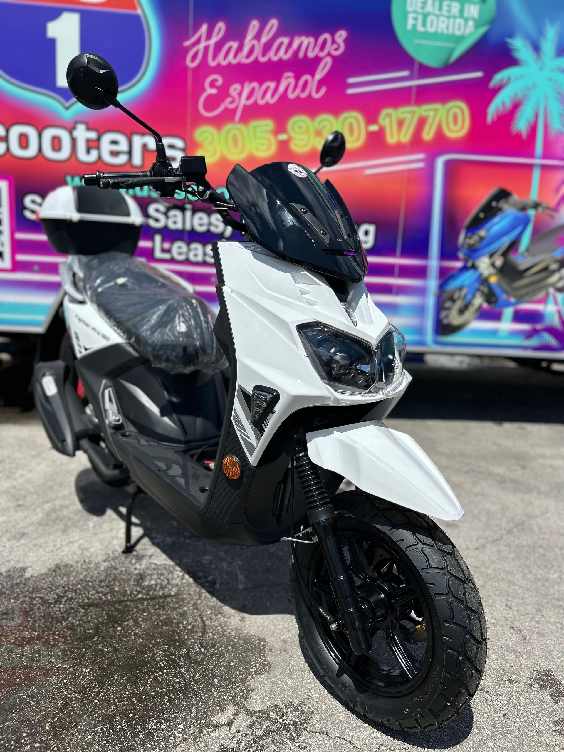 White and black scooter parked on pavement, with 