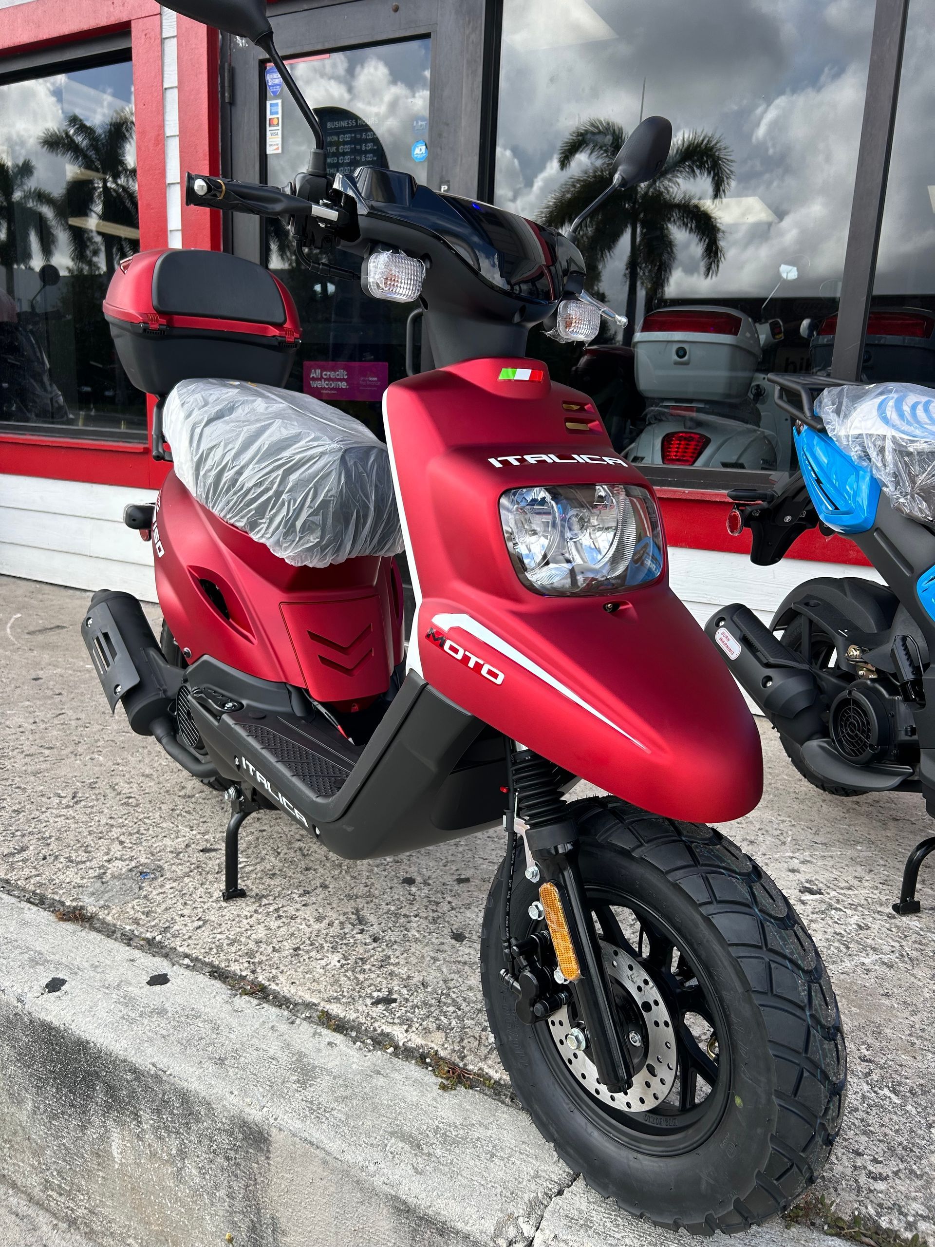 Red scooter with black accents parked outside a store.