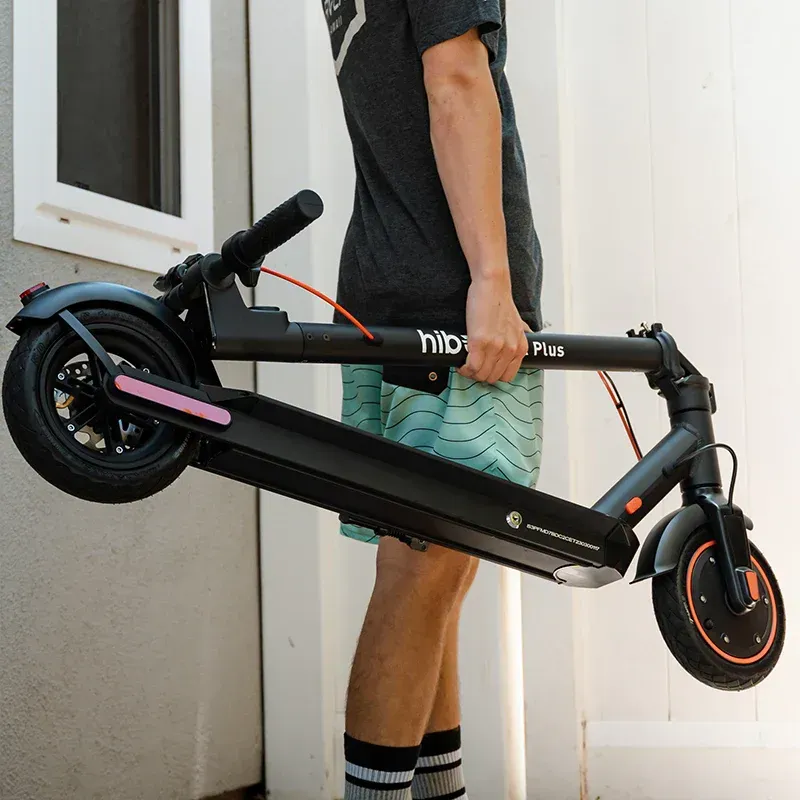 Black electric scooter with red accents, kickstand down, angled view.
