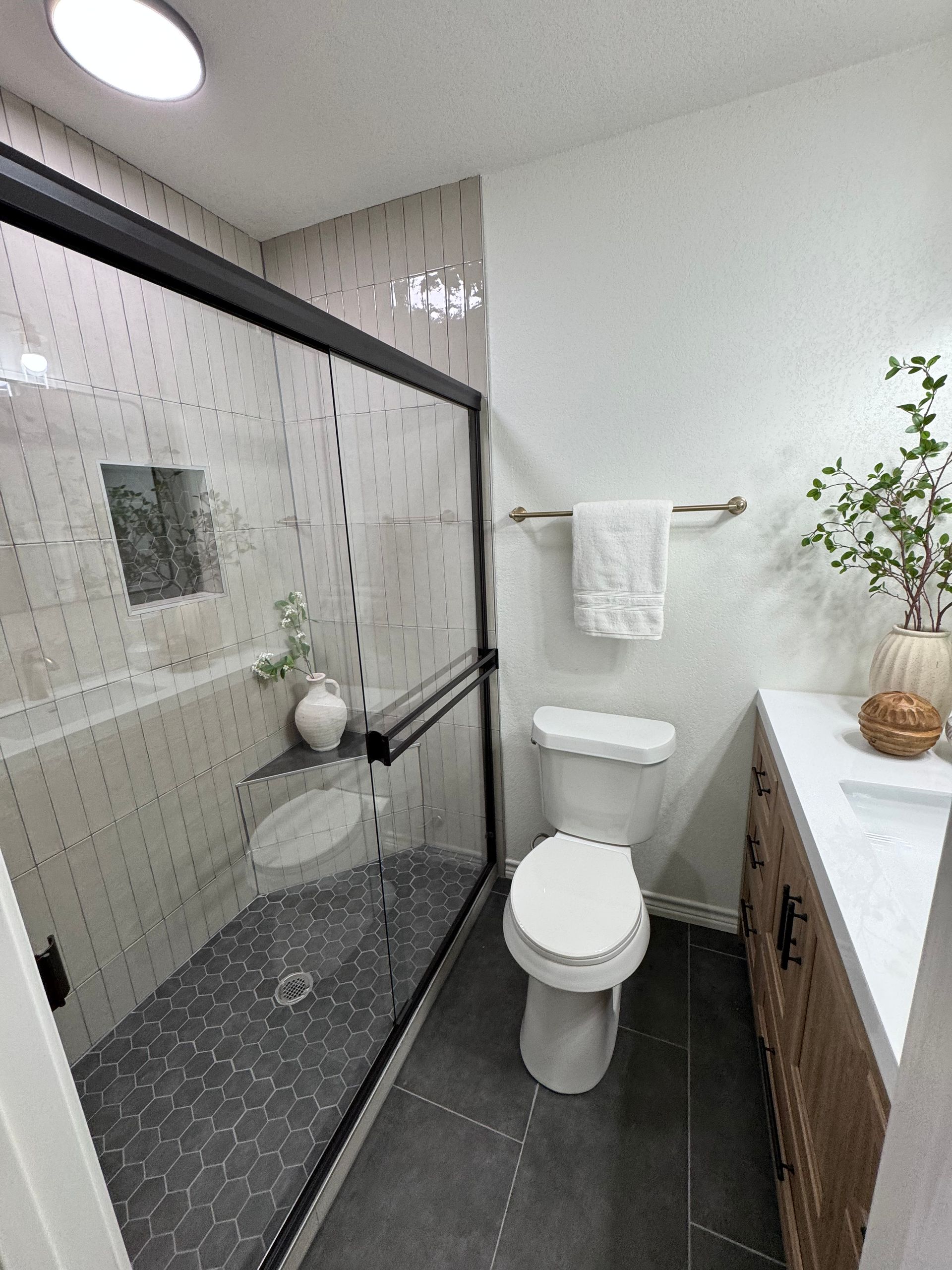 House with stone facade and columns illuminated at dusk. Lush green lawn and colorful sky.