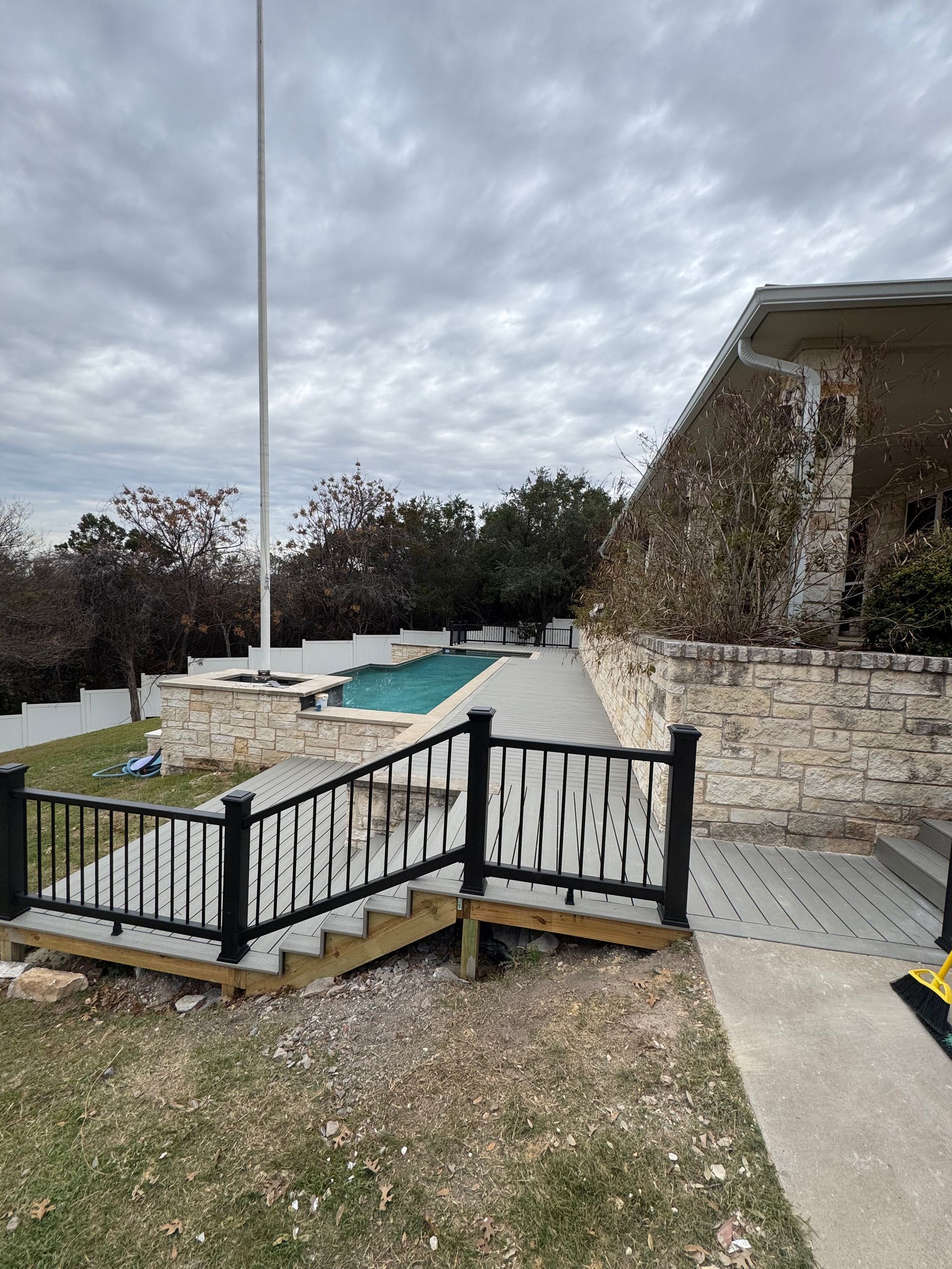 Wooden deck with outdoor furniture overlooking a golf course, surrounded by tall trees.