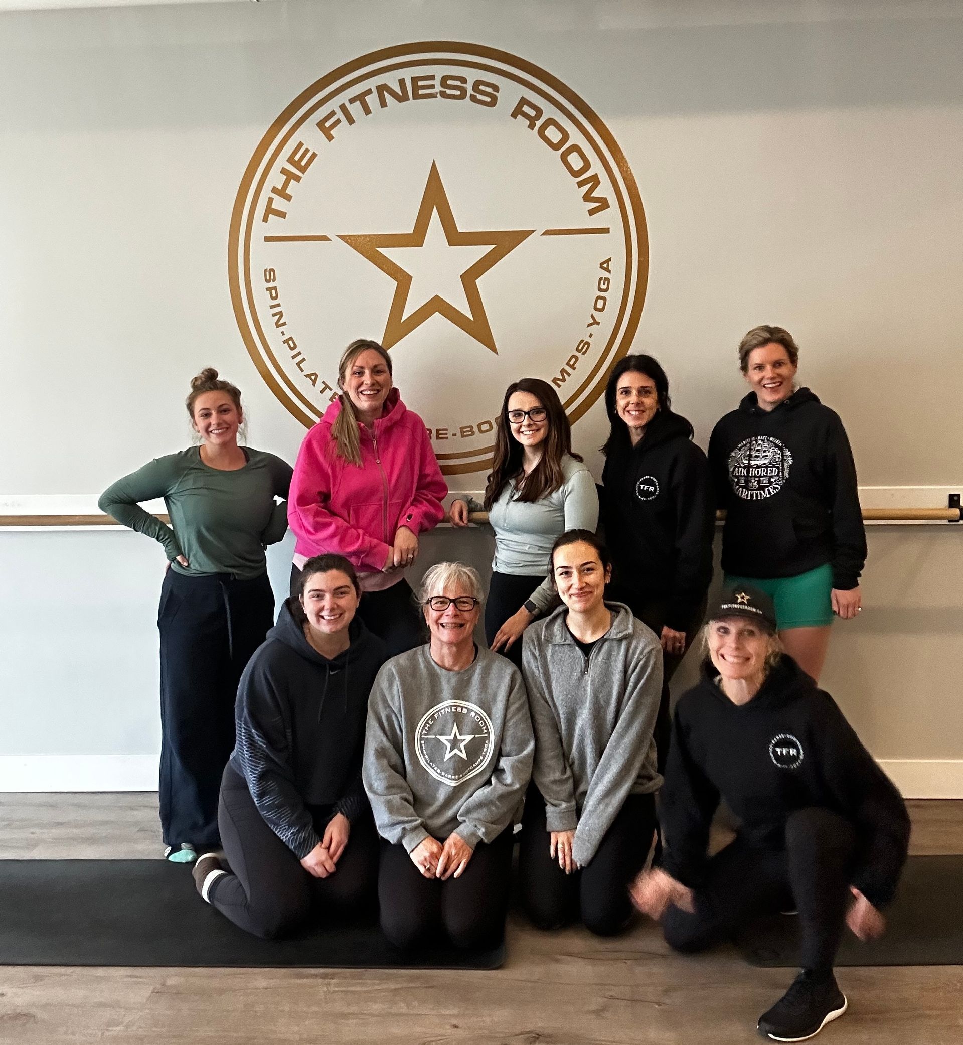 A group of people posing for a picture in front of a sign that says the fitness room