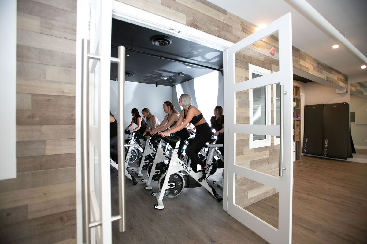 A group of people are riding exercise bikes in a gym.