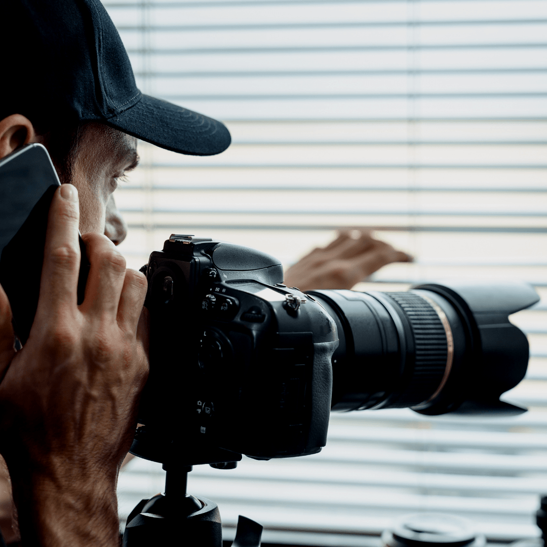 A man is taking a picture with a camera while talking on a cell phone.