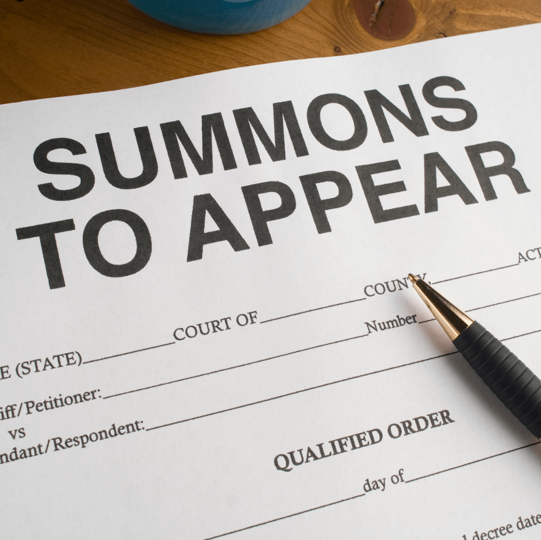 A summons to appear form with a pen on it