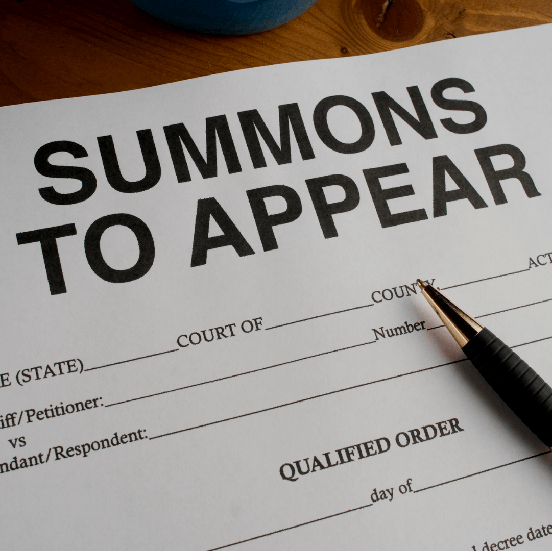 A summons to appear form with a pen on it