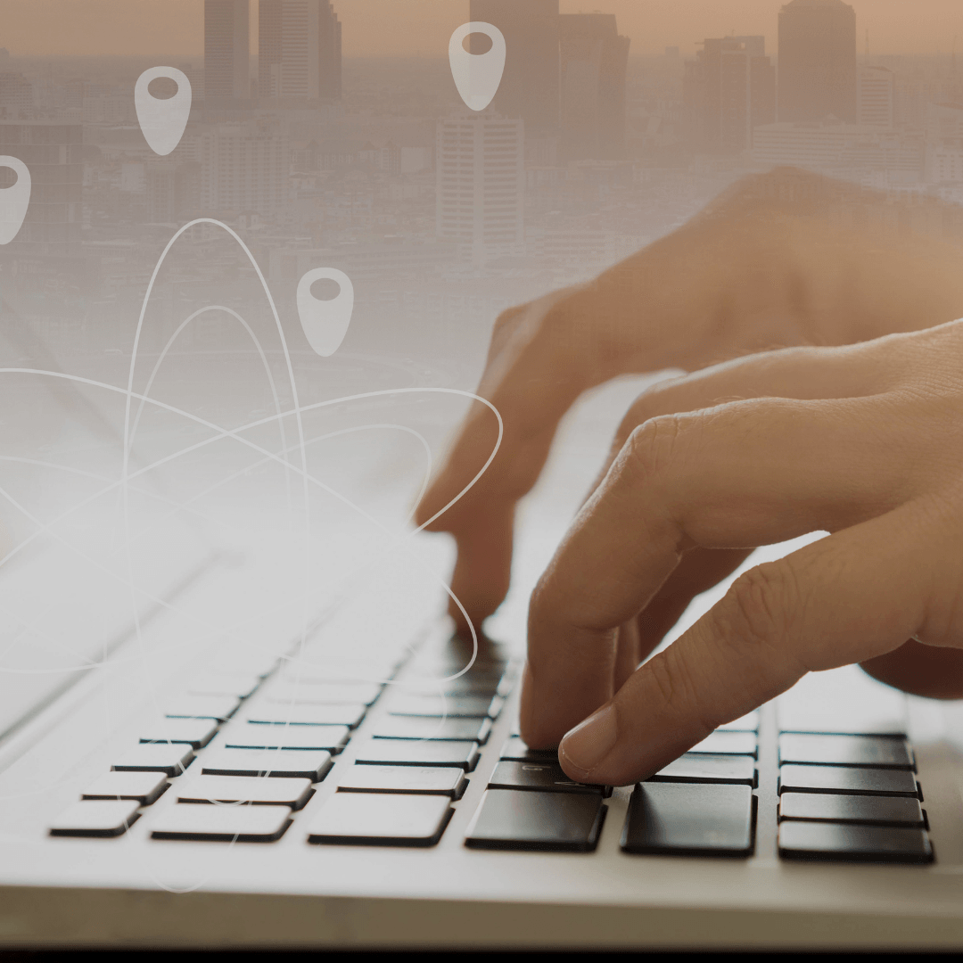 A person is typing on a laptop with a city in the background